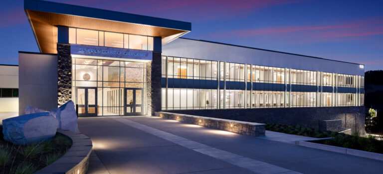 Modern Superior Court of California building at dusk, with a glass facade, lit interior, and broad entrance walkway