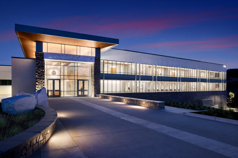 Modern Superior Court of California building at dusk, with a glass facade, lit interior, and broad entrance walkway