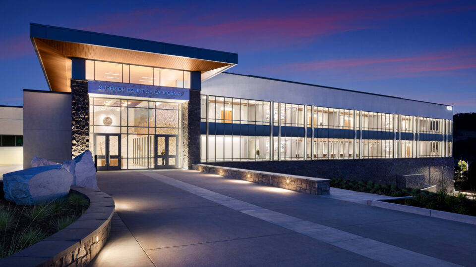 Modern Superior Court of California building at dusk, with a glass facade, lit interior, and broad entrance walkway