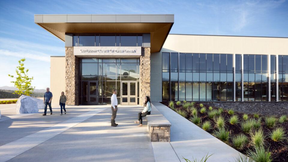 Modern Superior Court of California building with glass facade, stone columns, and people outside on the plaza