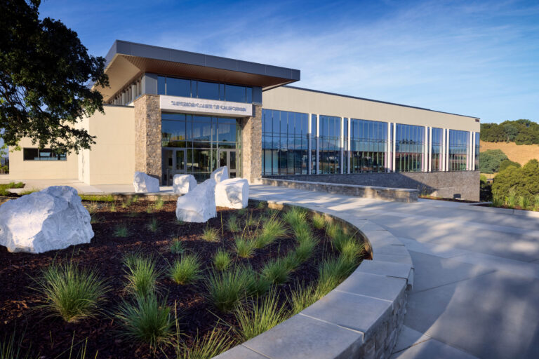 Modern courthouse building with glass walls, stone entrance, and landscaped walkway; sign reads Superior Court of California