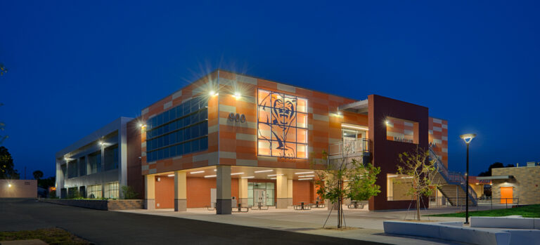 Modern school building at dusk with lit windows, a large panther graphic, and the number 900 on the facade