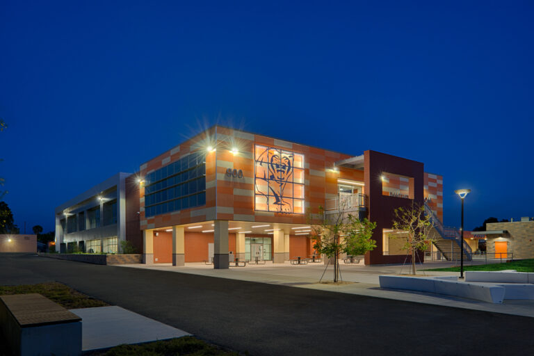 Modern school building at dusk with lit windows, a large panther graphic, and the number 900 on the facade