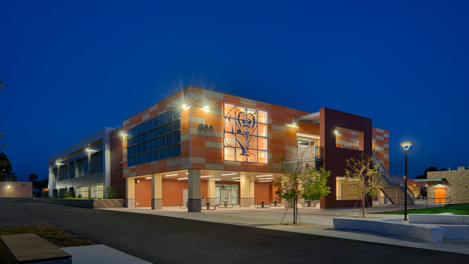 Modern school building at dusk with lit windows, a large panther graphic, and the number 900 on the facade
