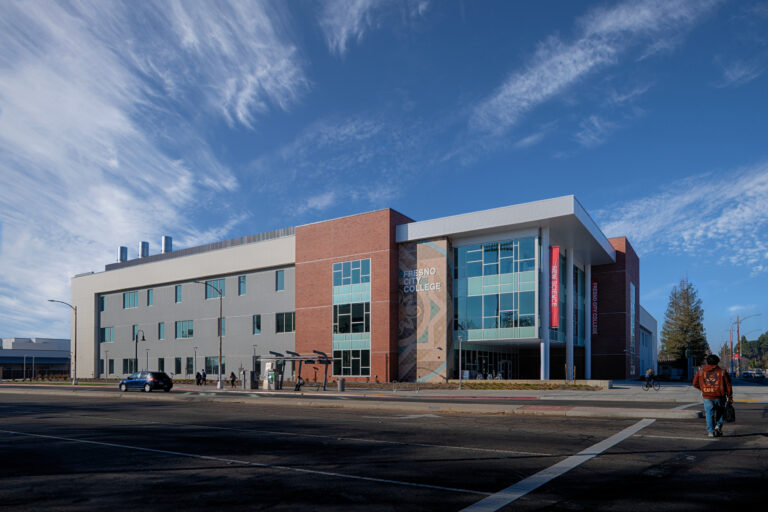 Fresno City College science building at a street corner, with brick and glass facade under a bright blue sky.