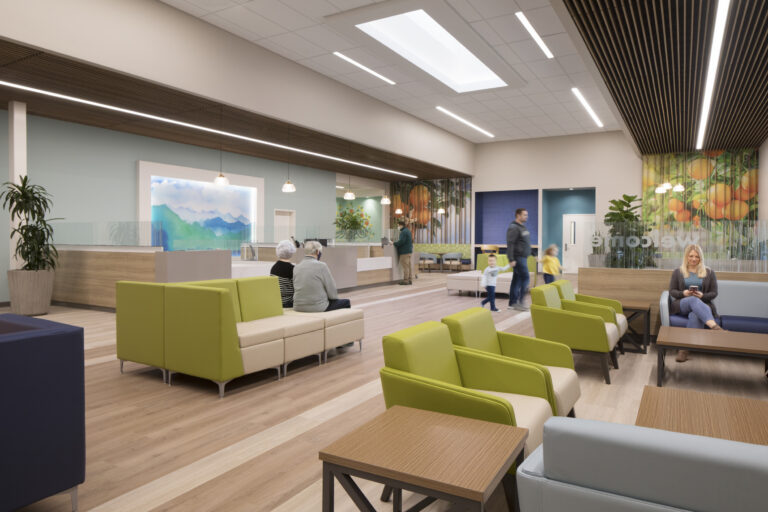 Modern clinic waiting room with green chairs, reception desks, and several adults and children seated or walking.