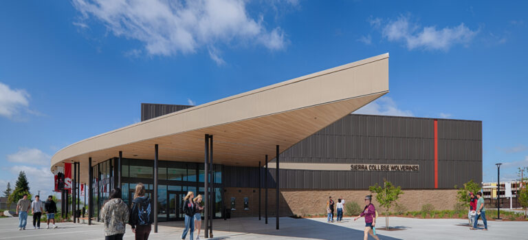 Students walk outside the Sierra College Wolverines building beneath a large angled canopy on a sunny day.