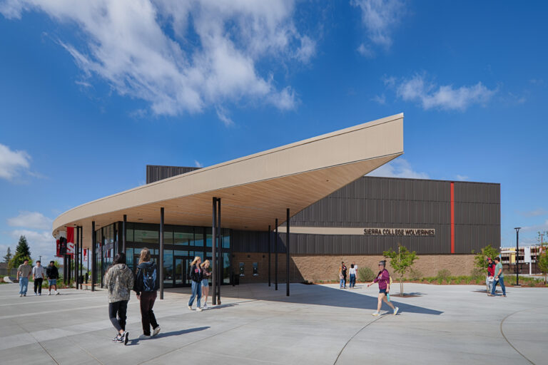 Students walk outside the Sierra College Wolverines building beneath a large angled canopy on a sunny day.