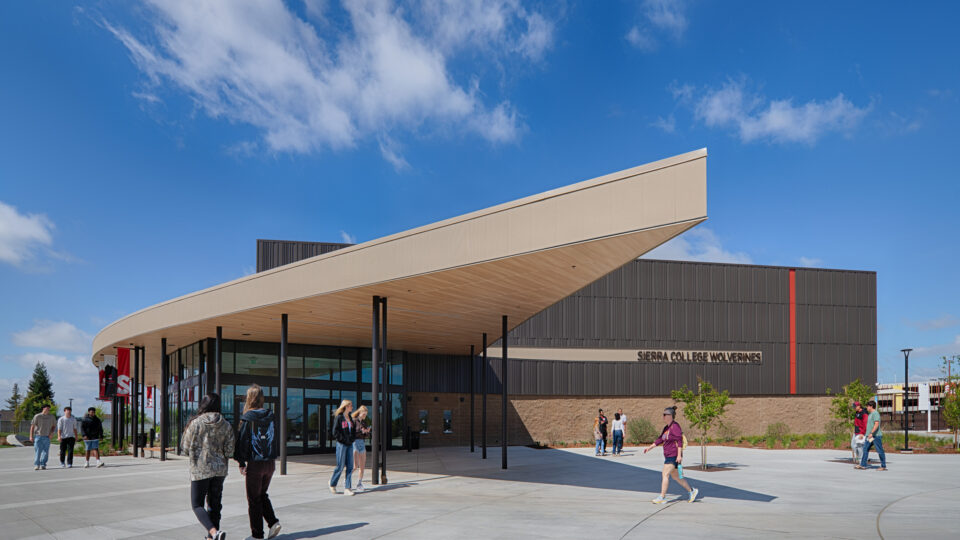 Students walk outside the Sierra College Wolverines building beneath a large angled canopy on a sunny day.