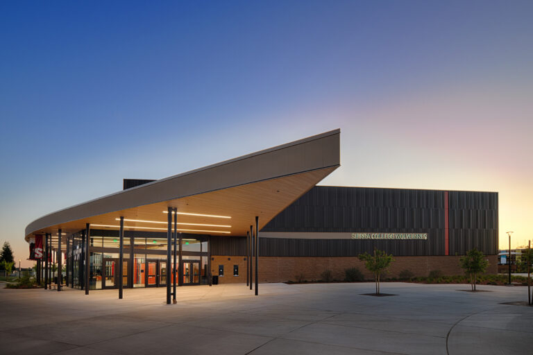 Modern Sierra College Wolverines building at dusk with a dramatic angled roof, glass entrance, and open plaza