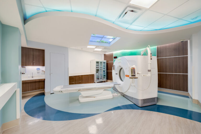 Modern hospital CT scan room with a white scanner, wood cabinets, and blue ambient ceiling lighting