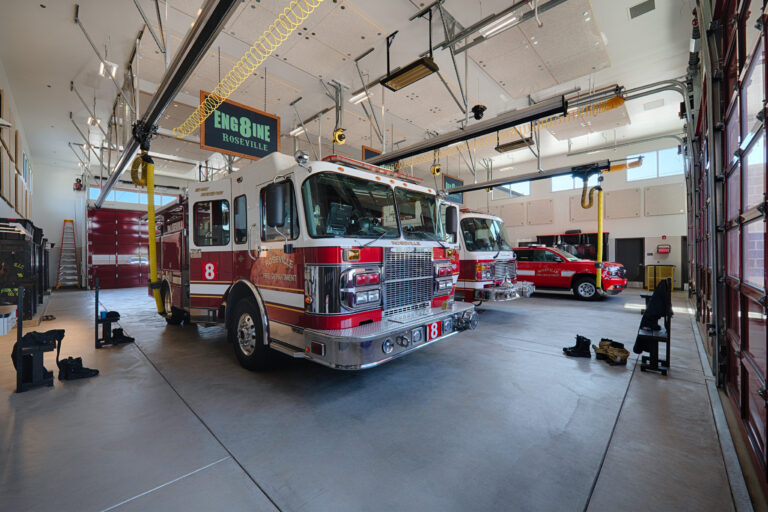 Roseville Fire Department engine and rescue vehicles parked inside a bright fire station bay marked Engine Roseville