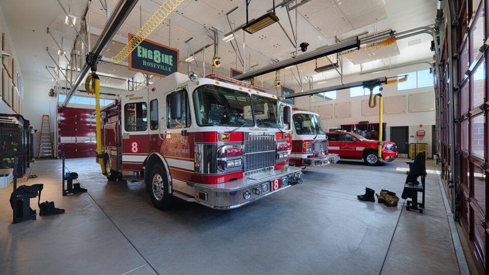 Roseville Fire Department engine and rescue vehicles parked inside a bright fire station bay marked Engine Roseville