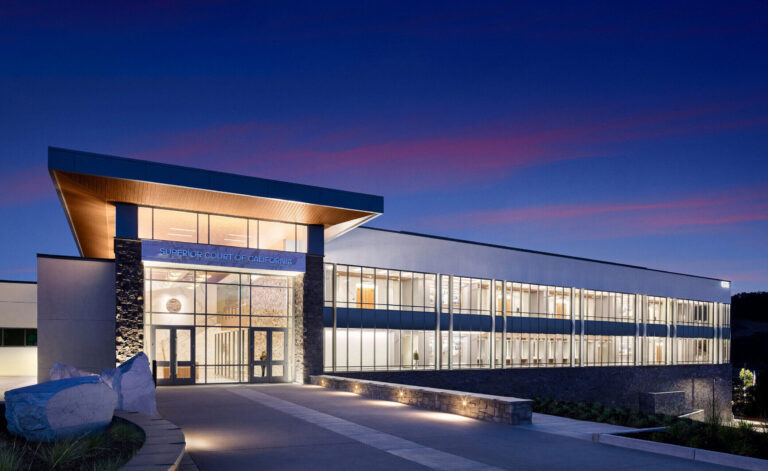 Modern Superior Court of California building with a glass facade glowing at dusk under a blue and pink sky