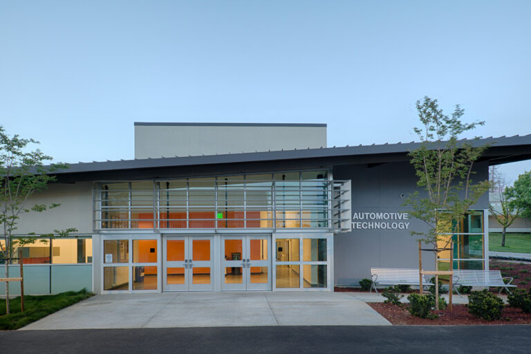 Modern building entrance with large glass doors and a sign reading Automotive Technology