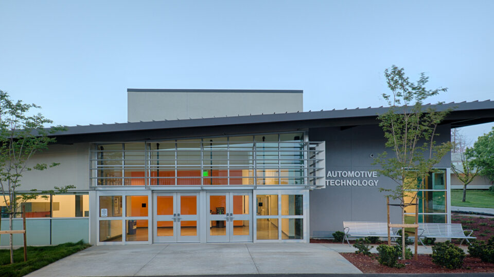 Modern building entrance with large glass doors and a sign reading Automotive Technology