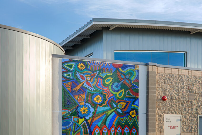 Modern building with a colorful mosaic mural on the wall under a blue sky