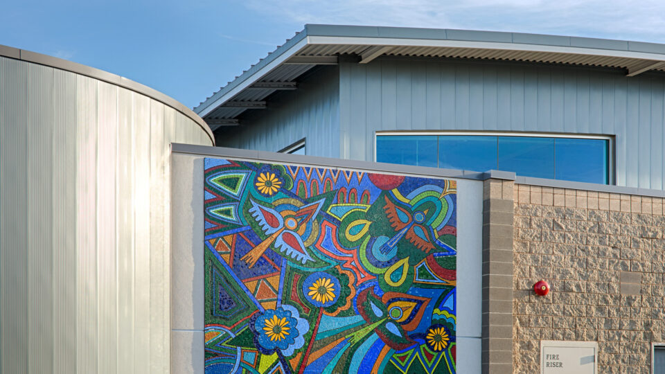Modern building with a colorful mosaic mural on the wall under a blue sky