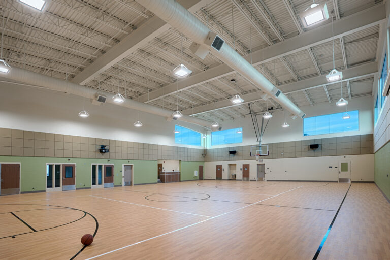Empty indoor basketball gym with a single basketball on the court and high ceilings with skylights