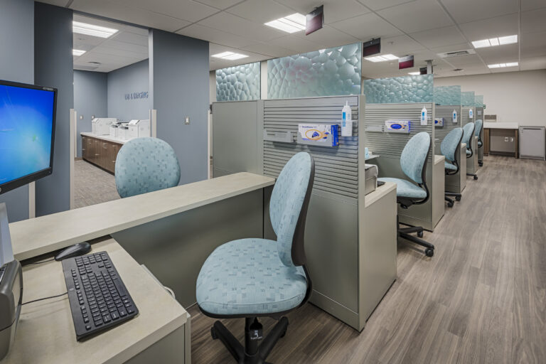 Empty medical office with blue chairs, cubicles, and computers in a lab and imaging area