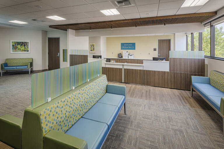 Modern pediatric clinic waiting room with colorful benches, reception desk, and large windows
