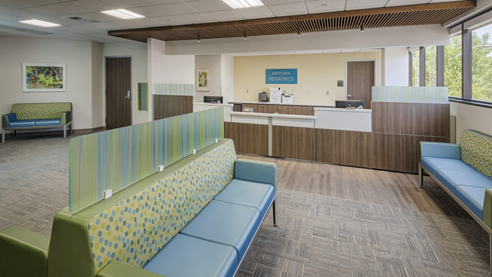 Modern pediatric clinic waiting room with colorful benches, reception desk, and large windows