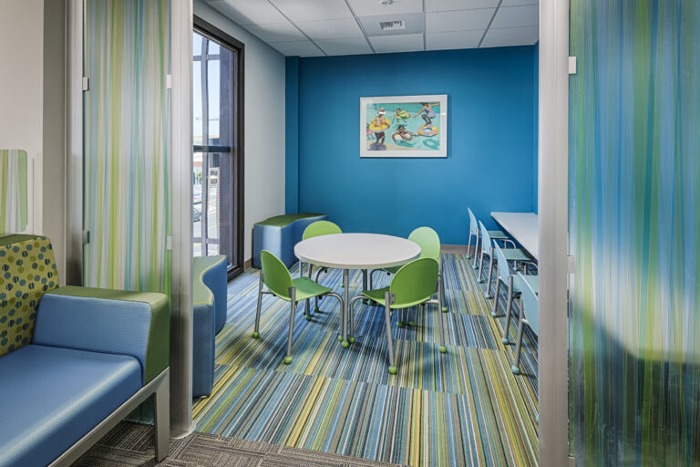 Colorful modern meeting room with round table, green chairs, and striped carpet