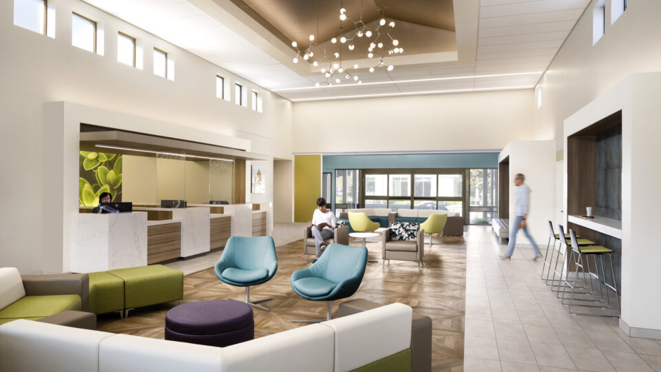 Modern, bright lobby lounge with colorful seating, a reception desk, and people sitting and walking inside