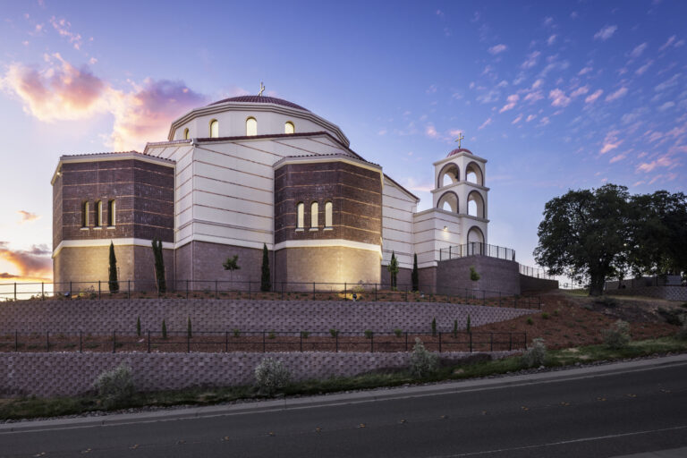 A large church with a dome and bell tower at sunset under a pink-blue sky