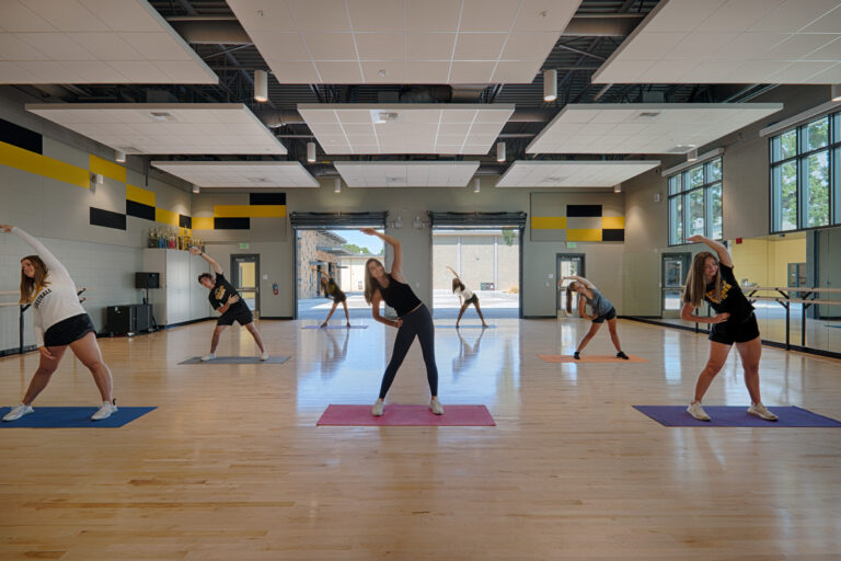 Teen dancers stretching in a bright studio, each on a yoga mat in a side-bend pose
