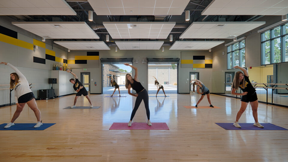 Teen dancers stretching in a bright studio, each on a yoga mat in a side-bend pose