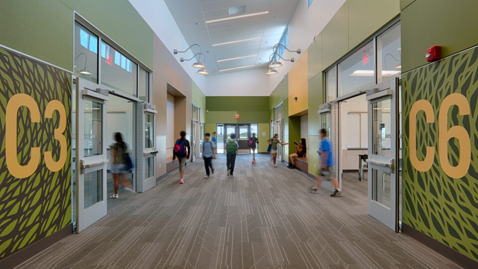 Modern school hallway with students walking past classroom doors marked 3C3 and C6