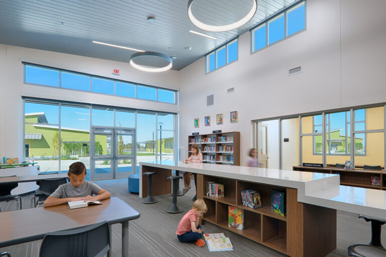 Bright modern library with children reading at tables and on the floor, large windows, and circular ceiling lights