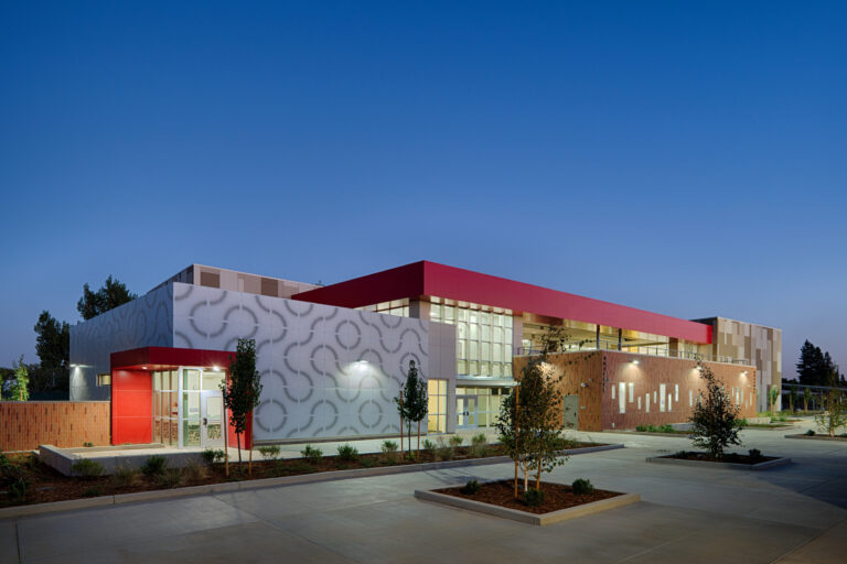 Modern school building with red accents and patterned exterior walls at dusk
