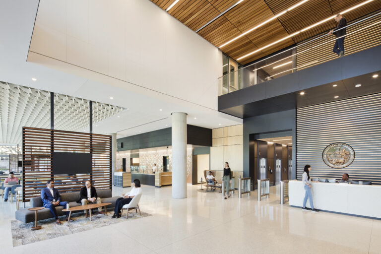 Modern government office lobby with reception desk, seating area, and a California state seal on the wall