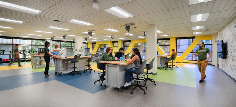 Modern makerspace with people collaborating at worktables in a bright classroom-like office