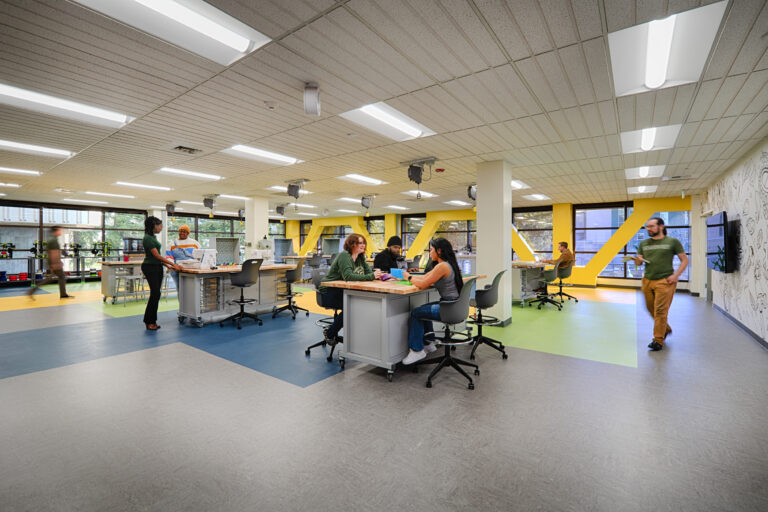 Modern makerspace with people collaborating at worktables in a bright classroom-like office
