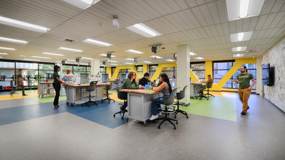 Modern makerspace with people collaborating at worktables in a bright classroom-like office