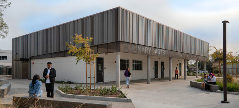 Modern campus building labeled Culinary Arts with students sitting and walking outside on a courtyard plaza