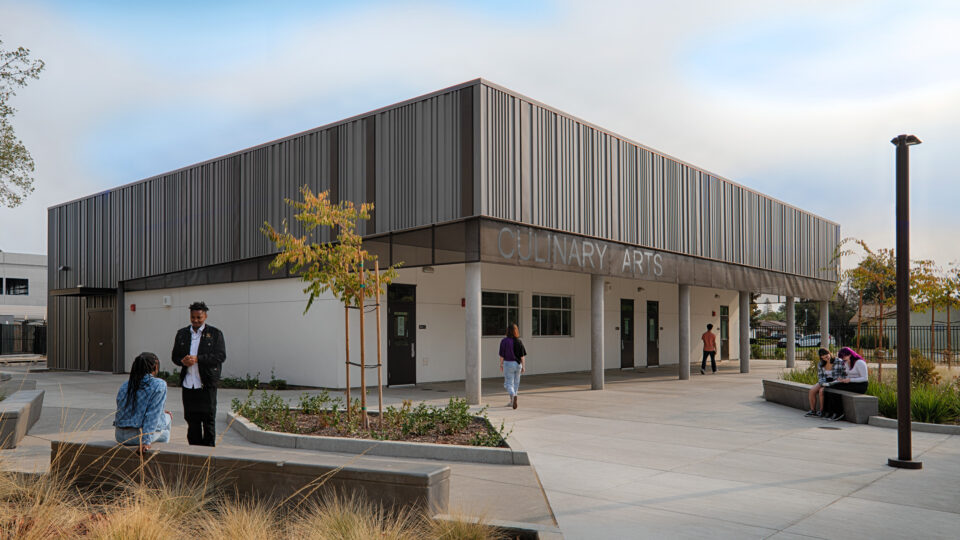 Modern campus building labeled Culinary Arts with students sitting and walking outside on a courtyard plaza
