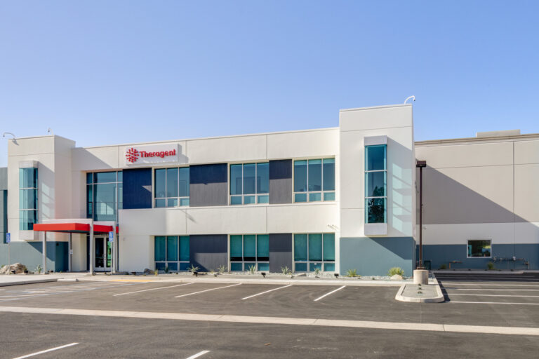 Modern Theragent office building with a mostly empty parking lot under a clear blue sky