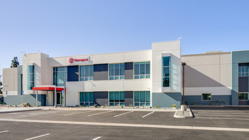 Modern Theragent office building with a mostly empty parking lot under a clear blue sky