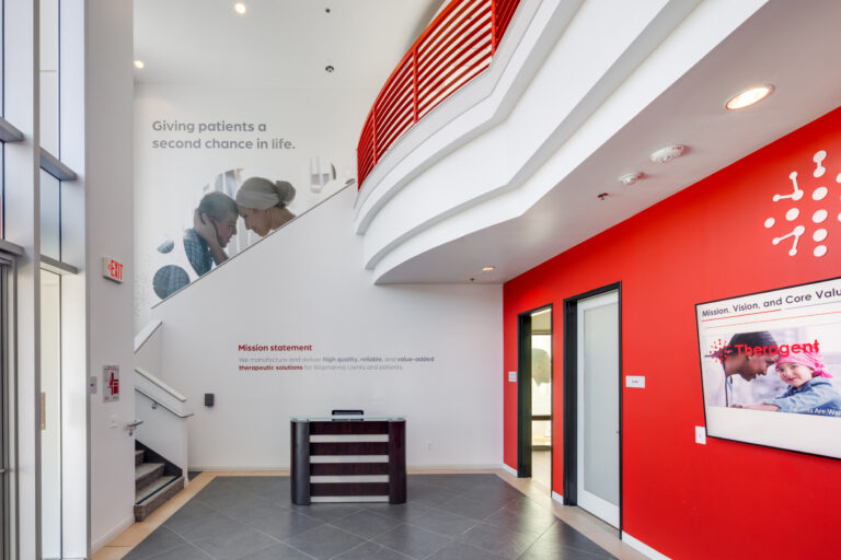 Modern lobby with red accent wall, curved balcony, reception desk, and health-related wall text and imagery
