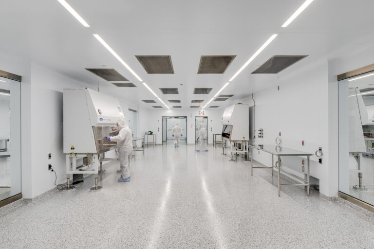 Cleanroom with technicians in protective suits working at laboratory safety cabinets