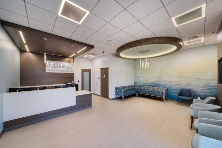 Modern medical clinic reception area with UCI Health signage, waiting chairs, and soft blue ocean wall mural