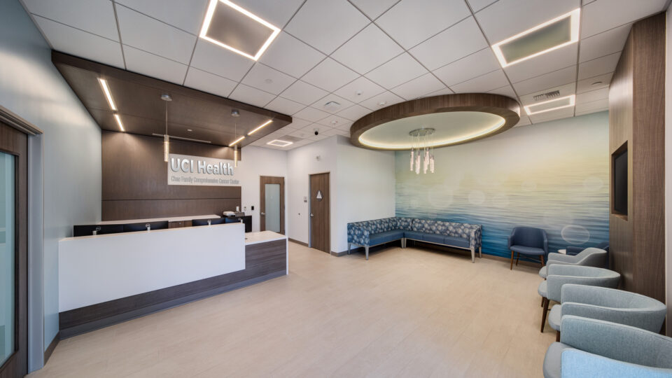 Modern medical clinic reception area with UCI Health signage, waiting chairs, and soft blue ocean wall mural
