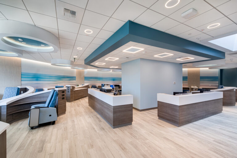 Modern medical reception area with curved check-in desks, blue accents, and bright circular ceiling lights