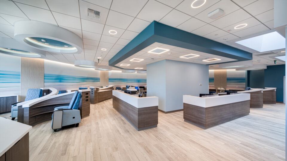 Modern medical reception area with curved check-in desks, blue accents, and bright circular ceiling lights