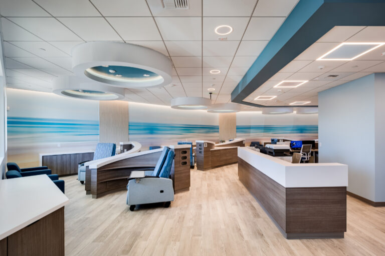 Modern empty medical clinic reception area with curved desks, blue chairs, and circular ceiling lights