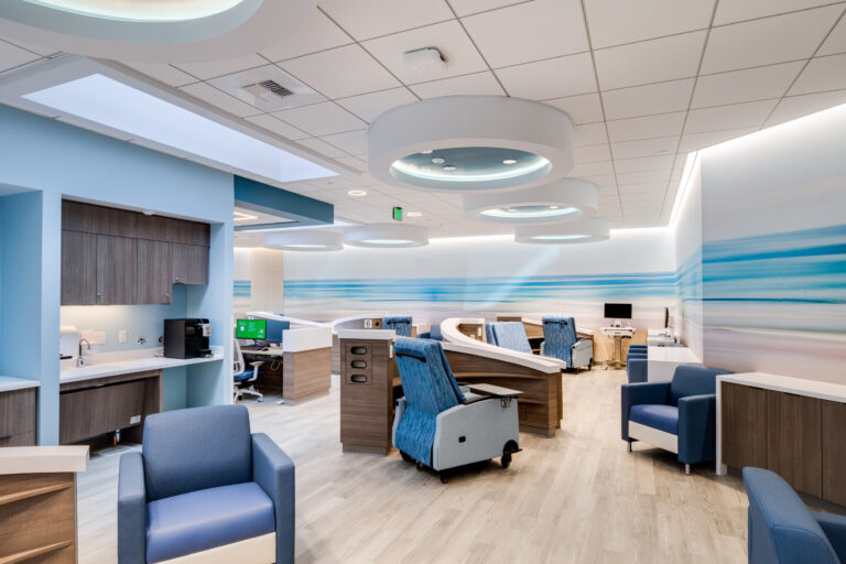 Modern hospital waiting area with blue chairs, curved desks, and ocean-themed wall murals